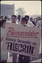 Man holding poster that reads, "Bienvenidos Heroicos Tripulantes del Alecrin"