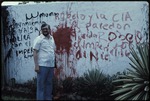 Alfonso Robelo standing next to a wall with red grafitti