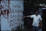 Alfonso Robelo pointing to a wall with red grafitti