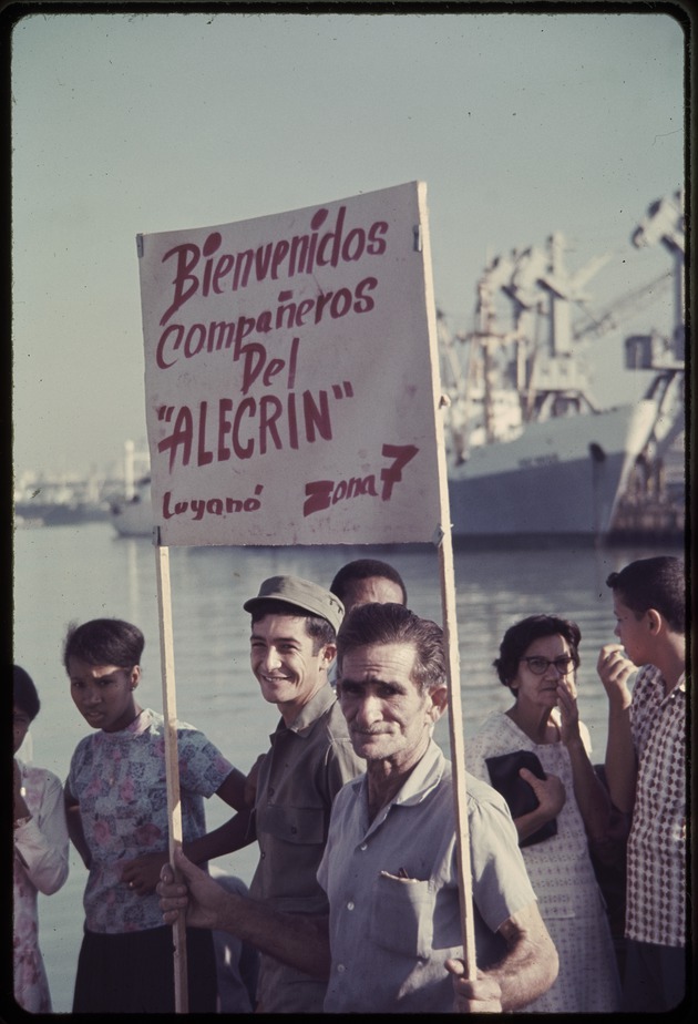 Man holding sign reading "Bienvenidos companeros del 'Alecrin' Zona 7"