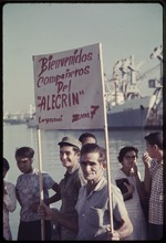 Man holding sign reading Bienvenidos companeros del 'Alecrin' Zona 7