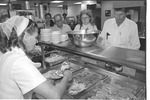 Cafeteria employee serving food to students