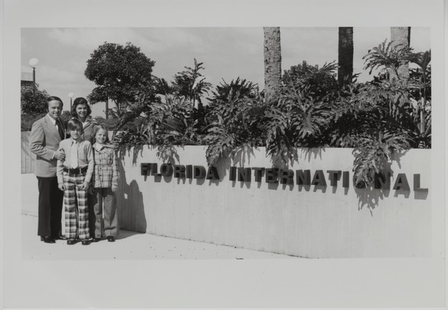 The Perry family standing next to the Florida International University sign on Tamiami Campus