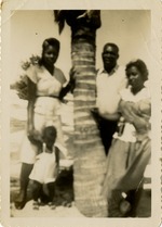 Family poses next to palm tree