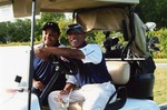 Two men pose in golf cart