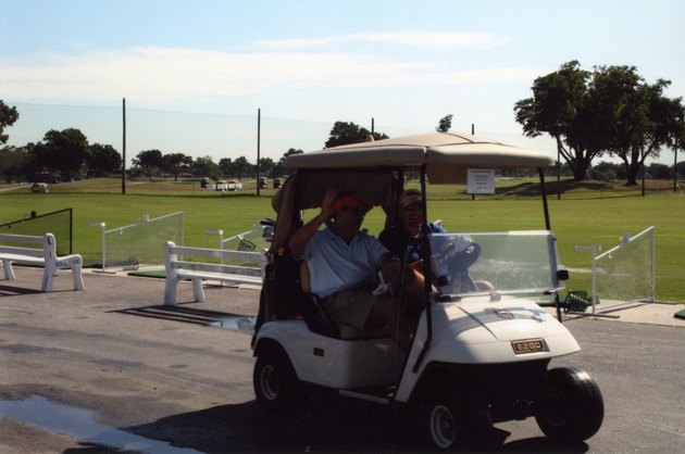 Two men driving golf cart