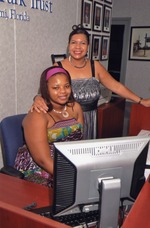 Two women pose behind desk