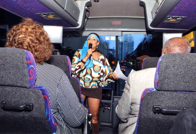 Woman at front of bus speaks to passengers