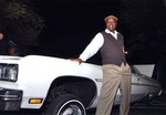 Guy Forchion poses in front of vintage car