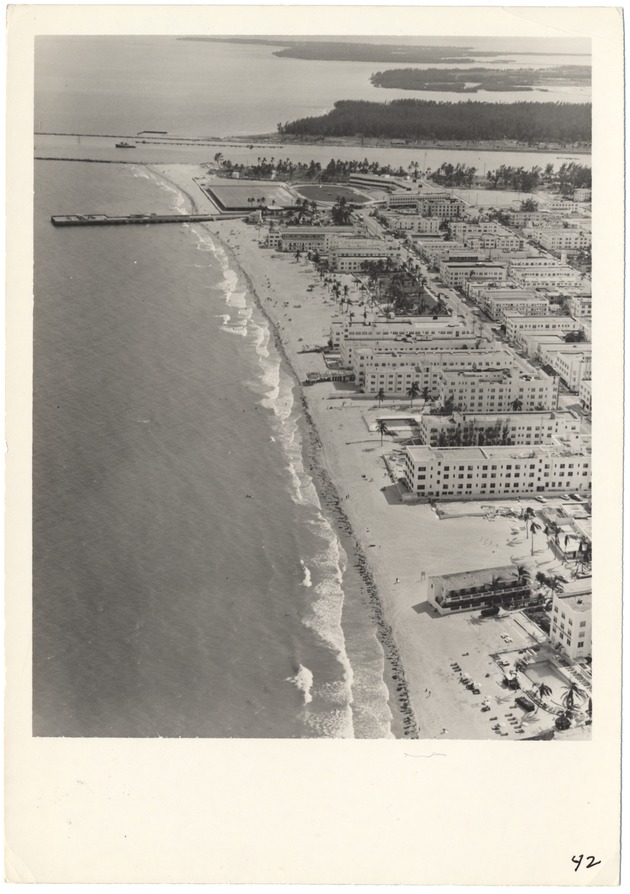 1950s and 1960s Aerial views of South Beach - Photograph, recto: [Looking south along the ocean from about Fourth Street showing Fisher Island, Government Cut, the dog track, and oceanfront hotels]