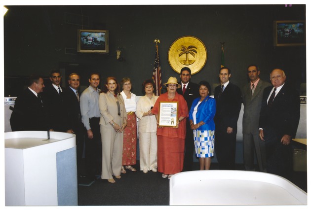 Posthumous achievement award ceremony for Ed Resnick - Photograph, recto: [Phyllis Resnick accepting a proclamation honoring the life and achievements of the late Ed Resnick. From L to R: Commissioners Luis R. Garcia, Jr., Saul Gross, Jose Smith,  the Resnick Family, Mayor David Dermer, and Commissioners Matti Bower, Richard Steinberg and Simon Cruz, September 10, 2003]