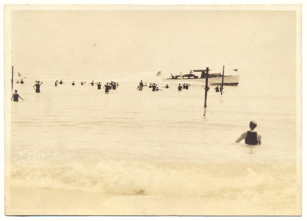 Miami Beach swimmers - Photograph, recto: [Swimmers looking at a boat with an American flag].