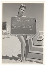 Dolores Kirby holding a Welcome to Miami Beach sign