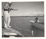 Men on two different boats catching fish