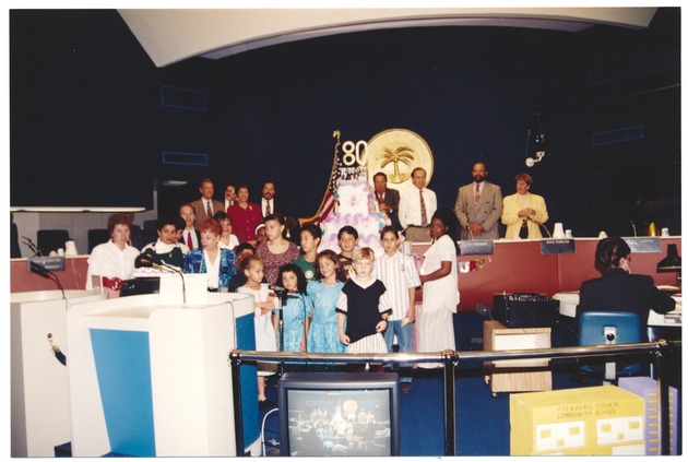 Miami Beach 80th Anniversary and other Convention Center events, 1994-1995 - Photograph, recto: [City commission, childre, and residents celebrate the 80th anniversary of Miami Beach with a cake. In the background: Commissioner Martin Shapiro, Susan Gottlieb, Niesen Kasdin, Sy Eisenberg, David Pearlson, and Nancy Liebman].