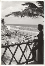 Woman on balcony overlooking private hotel beach, November 1953