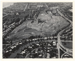 Aerial view of golf course and houses with the ocean and hotels in the upper left