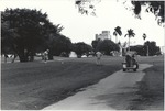 Golfer Taking an Opening Drive as Golf Cart Drives by