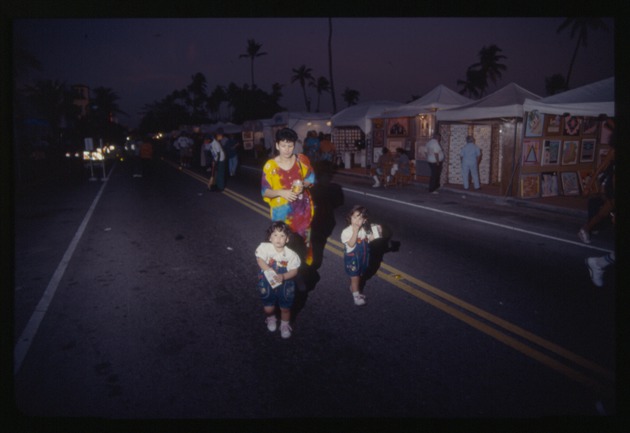 Woman and two children walk on street during Miami Beach Festival of the Arts