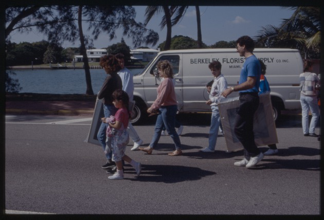 People walking on street holding canvases