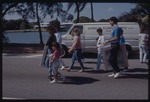 People walking on street holding canvases