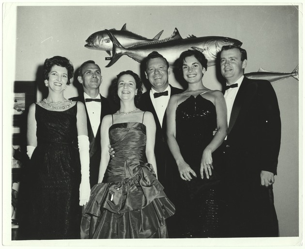 People in formal dress posing in front of fish taxonomy - Recto Photograph