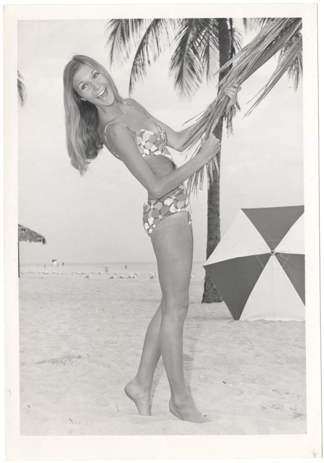 Dominique Doherty holding a palm tree with an umbrella in view - 