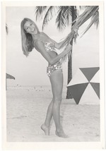 Dominique Doherty holding a palm tree with an umbrella in view
