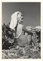 Sandy Steeves with a towel on her head sitting on coral rock