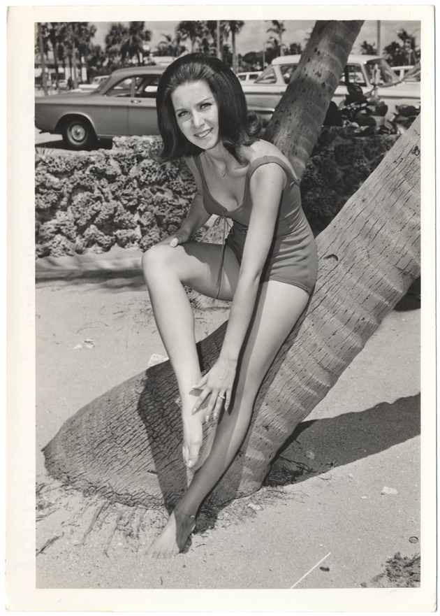 Francine Rubin next to a palm tree in front of parked cars - 
