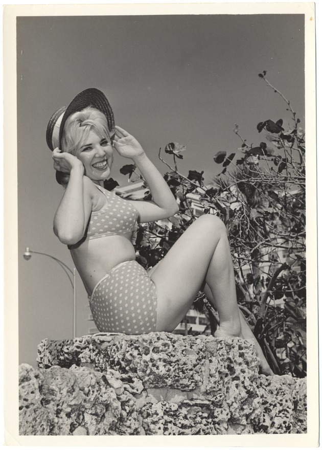 Melinie Smith wearing a beach hat on a coral rock wall - 