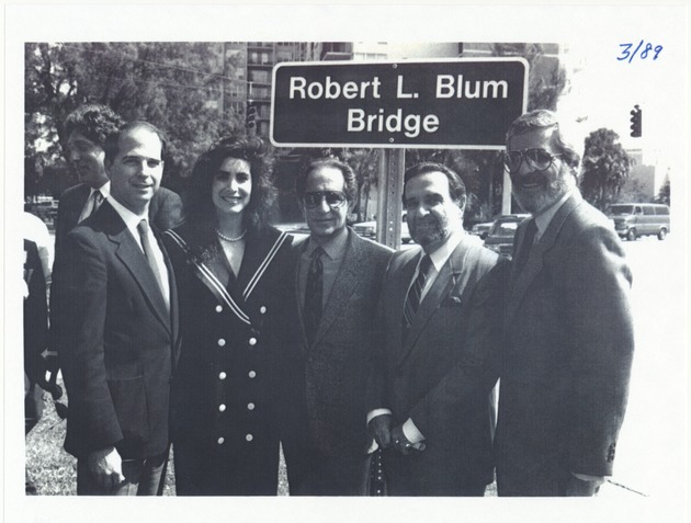 Community leaders posing at the dedication of the Robert L. Blum Bridge - Photocopy, recto: [(Left to right) Bruce M. Singer (City Commissioner & President/CEO Miami Beach Chamber of Commerce), Lisa Blum (Robert Blum's Daughter), Harvey Ruvin (Country Commissioner), Barton Goldberg (Chairman, Jefferson National Bank), and Stuart Blumberg (Chairman, Miami Beach Chamber of Commerce) in front of the Robert L. Blum Bridge (Forty-first Street from Pine Tree Drive to Indian Creek Drive over Indian Creek)]