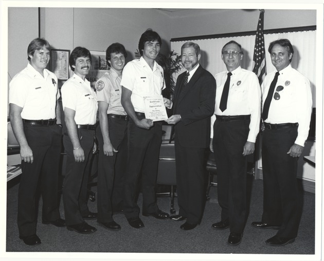 Miami Beach City Manager Rob Parkins and other officials at various events - Photograph, recto: [Fire rescue officers and Ray Roskey receiving a Certificate of Appreciation from CIty Manager Rob Parkins, ca. 1985]