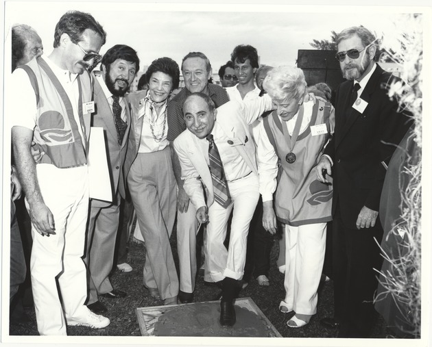 Charlie Cinnamon and Miami Beach events, 1987 - Photograph, recto: [Charles Cinnamon, center, makes his footprint on the cement at the Walk of Stars. (Left to right) ?, Commissioner Ben Grenald, ?, Sidney Weisburd, ?, Charles Cinnamon, ?, and City Manager Rob Parkins, ca. 1985]