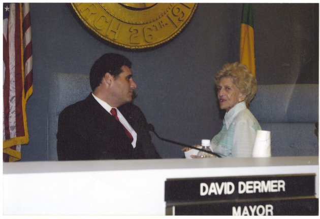 Bea Kalstein photographs and newspaper clippings, 2000s - Photograph, recto: [View of Mayor David Dermer talking to Miami Beach activist Bea Kalstein at a Commission Meeting, September 10, 2003]