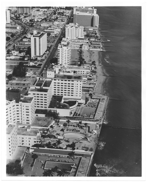 Aerial views of oceanfront buildings showing parks and beach erosion between Fisher Island and Halouver Pass, 1969 - Photograph, recto: [Aerial view of oceanfront buildings and pools before the 1980s beach rehabilitation projects]