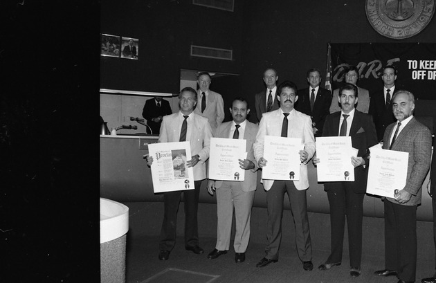 Miami Beach Commissioners and Mayor during Commission Meetings and Proclamations, 1990s - Negative: [View of City officials and awardees in the Commission Chambers. A banner of the D.A.R.E program in the back]