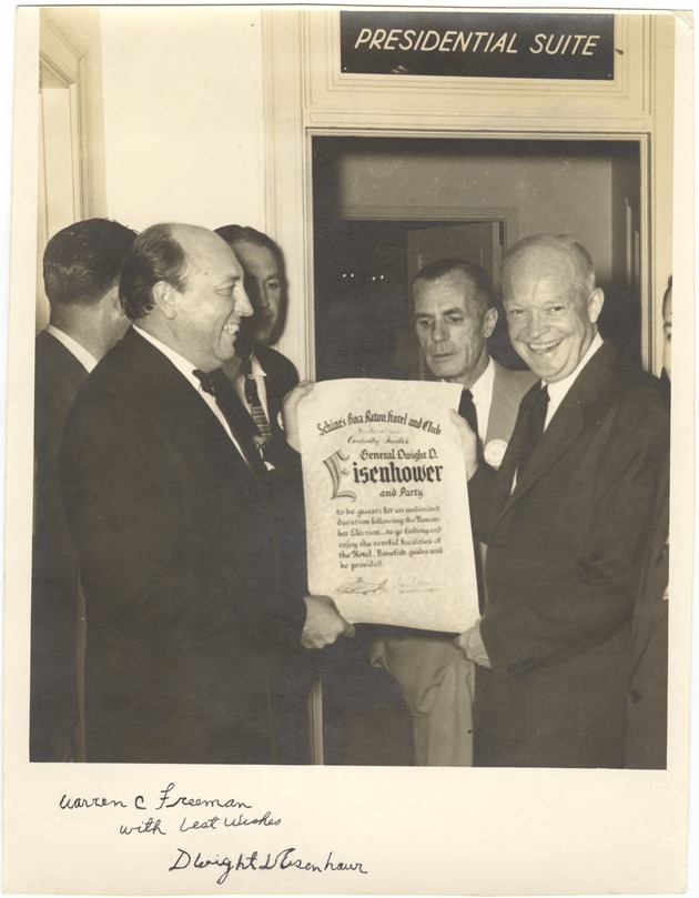 Photo of Dwight D. Eisenhower receiving an invitiation, standing in front of a Presidential Suite sign - Recto