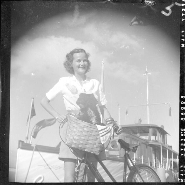 Woman posing with dog in a bicycle basket - Recto Photograph