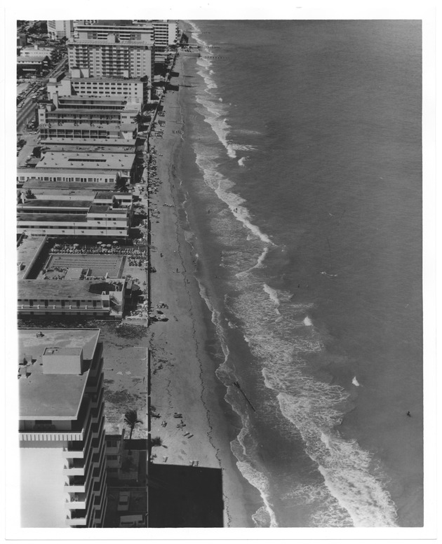 Aerial view of sandy area and buildings on the ocean front during high tide - Recto Photograph