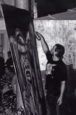 Male graffiti artist creating artwork on a board