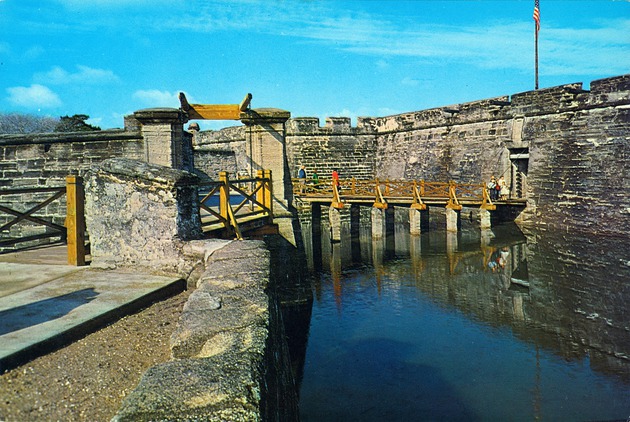 A large postcard showing the walking bridge and entrance to the Castillo de San Marcos, looking West, ca. 1965 - Front