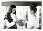 [Artifacts on display in the Pan American Center Museum with docents Janet Poole and Jean Babich, holding ceramic vessel]