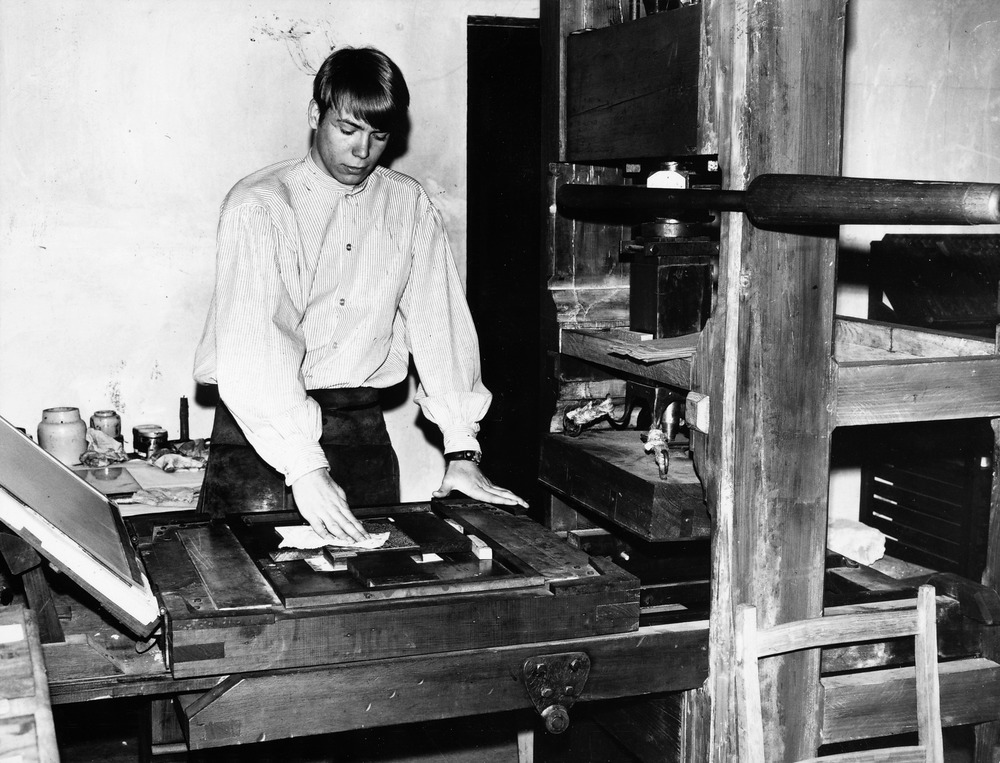 Dennis White doing a printing demonstration on the Restoration Commission's replica printing press, 1968