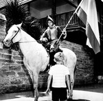 Boy in period dress riding on 'Mama,' the Restoration Commission's mare