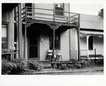 Woman sitting on the porch of 25 Spanish Street, looking East