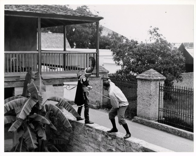 Two men from the Jaycee sword fighting troupe on the wall of the Salcedo House, looking Northeast, ca. 1965