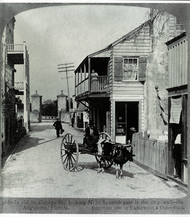 The North end of St. George Street with man on a cart being drawn by a cow and a woman on a balcony, looking North to the City Gates