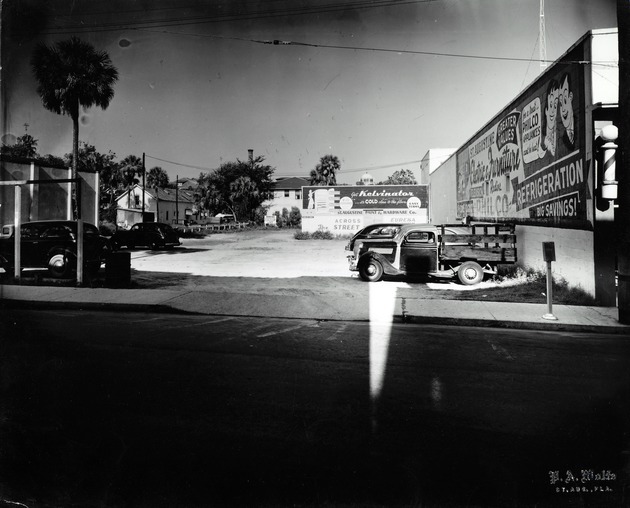 Spanish Street parking lot on left, St. Augustine Paint & Hardware Co. in center, and Partin Furniture on right, from St. George Street, looking West