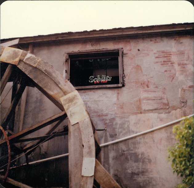 Portion of the water wheel and second story window of the Old Grist Mill as the Mill Top Tavern from the plaza directly to the North, looking South